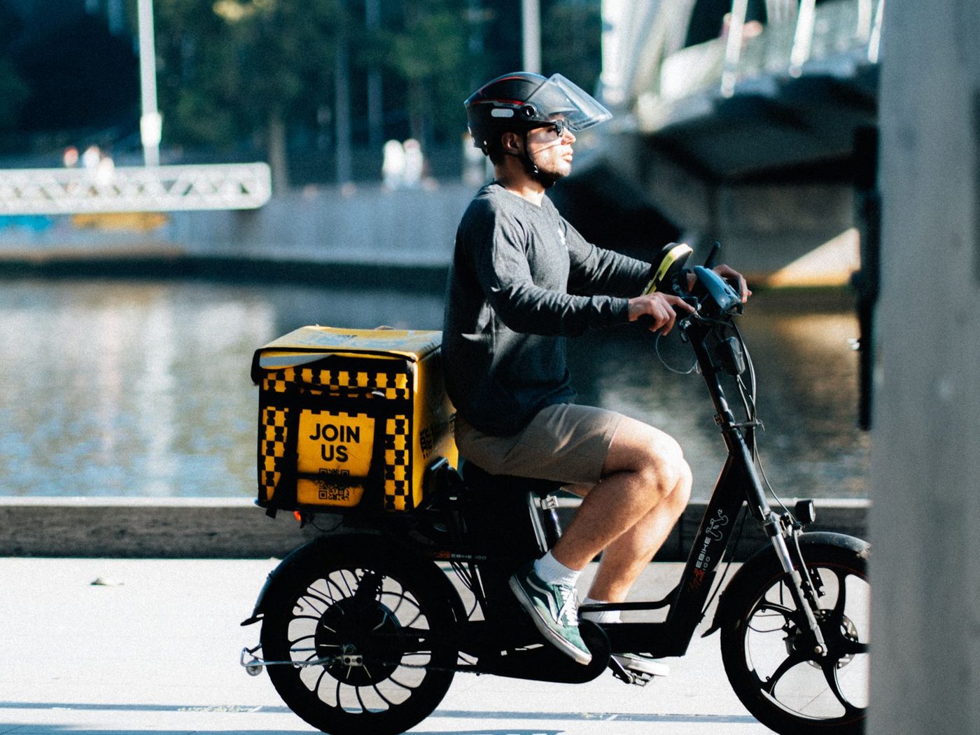 A delivery rider on an electric bike beside the Yarra River in Melbourne